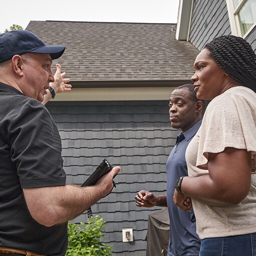 Roofing contractors outside home with homeowners 