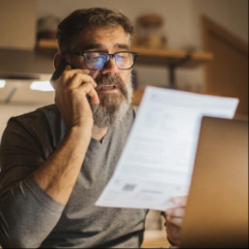 Man on phone holding up papers