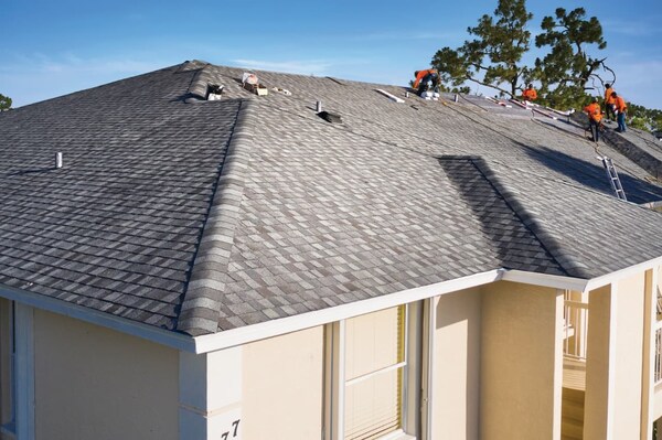 Roofing team installing new gray roof on stucco home