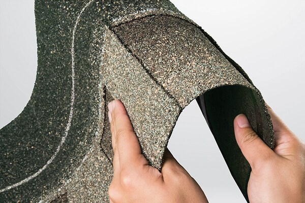 Hands bending a strip of Timberline ArmorShield II shingles, showing how flexible and durable it is.
