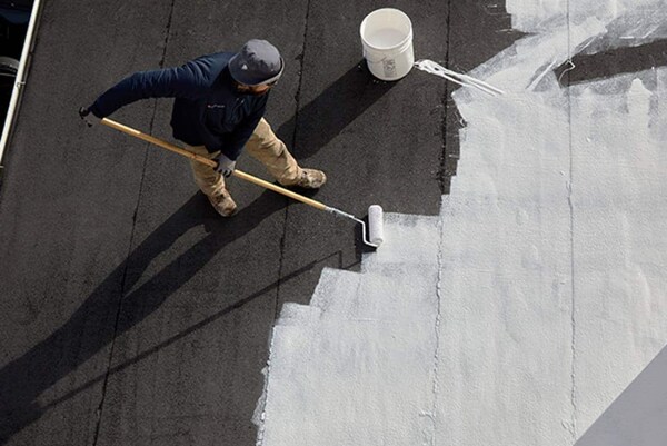 Roofing Contractor applying GAF coating on school rooftop